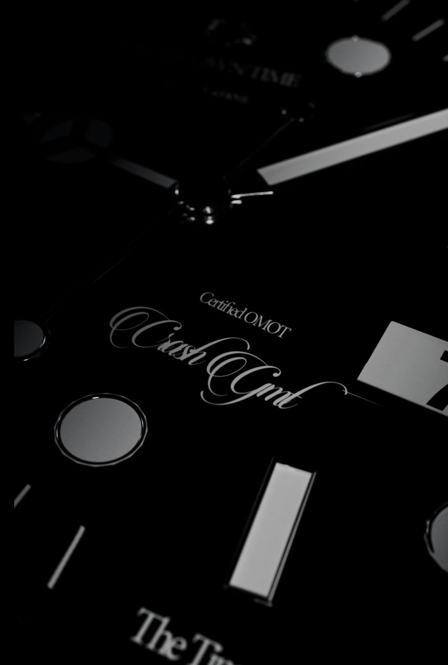 Macro de la esfera del Omot Crash GMT, con la caligrafía grabada sobre el negro